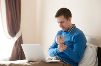 Image of man holding his wrist and looking at his computer